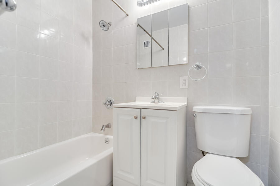Bathroom with full tub, tiled walls, mirrored medicine cabinet and vanity